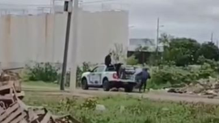 Fotograma del video donde se observa un patrullero policial estacionado junto a personas descargando bolsas de basura.