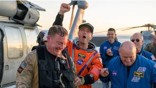 Cápsula espacial Orion de la NASA flotando en el Océano Pacífico tras el amerizaje, con equipos de recuperación alrededor.