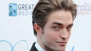 Robert Pattinson, actor, sonriendo en un evento público.
