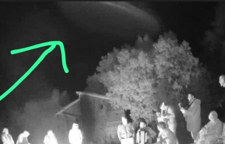 Fotografía en blanco y negro que muestra un objeto cilíndrico sobre un grupo de personas reunidas alrededor de un fogón durante el Primer Encuentro Ufológico Caá Catí