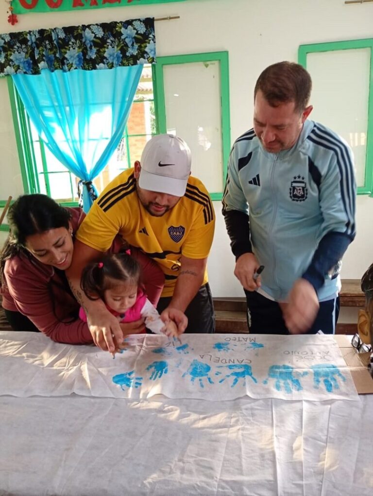 Niños del barrio Río Paraná posan con una bandera creada con sus manos