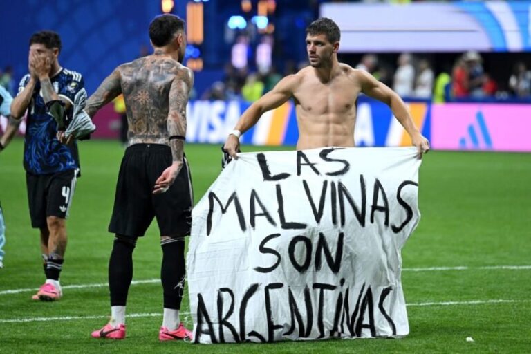 Futbolistas argentinos sostienen una bandera blanca con la frase Las Malvinas son argentinas en el césped del Mercedes-Benz Stadium