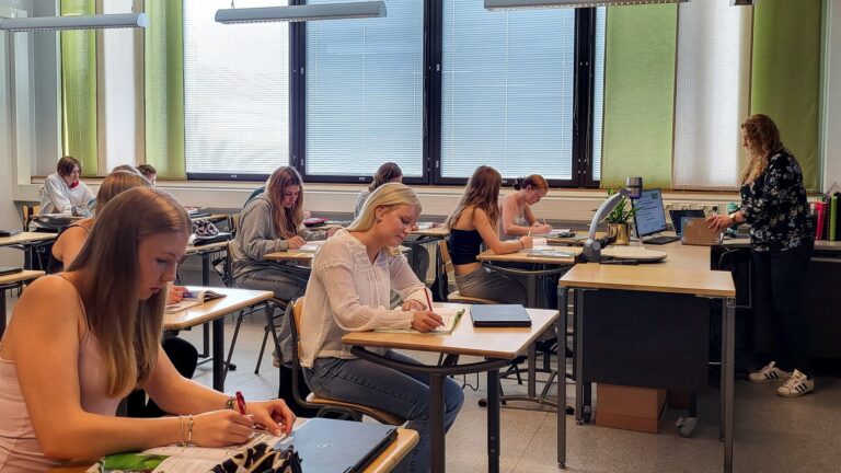 Docente frente a una computadora en un aula escolar
